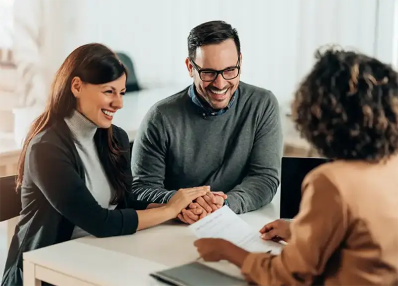 Happy couple meeting with an insurance advisor to review policy documents and coverage options.