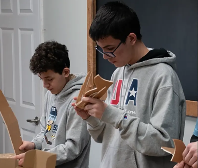 Students assembling wooden project pieces during a hands-on workshop or classroom activity.