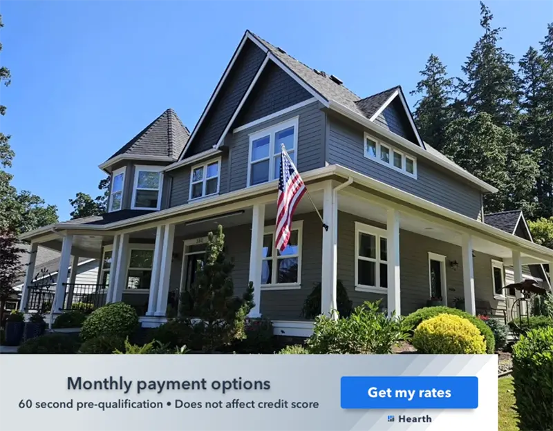 Large gray residential home with white trim, front porch, American flag, and monthly payment financing banner.