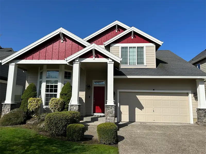 Residential home exterior with red accent siding, cream trim, stone columns, and a clean front entry.