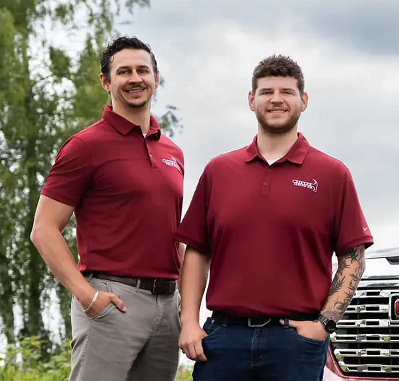 Sister Siding team members in branded red polos standing beside a company truck.