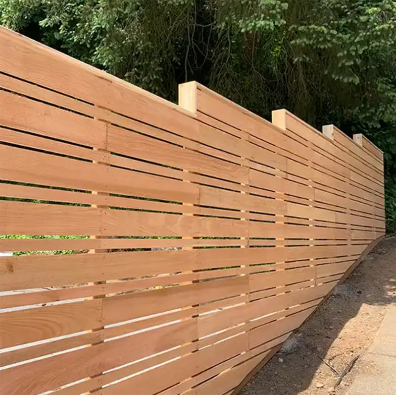 Modern horizontal wood privacy fence with narrow slat spacing along a landscaped property edge.